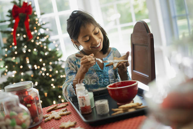 Молодая девушка украшает рождественское печенье — стоковое фото