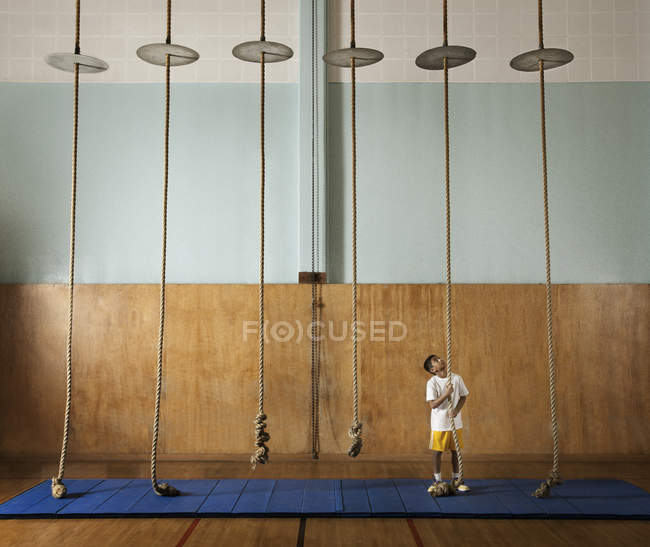 Niño escalando cuerda en un gimnasio - foto de stock