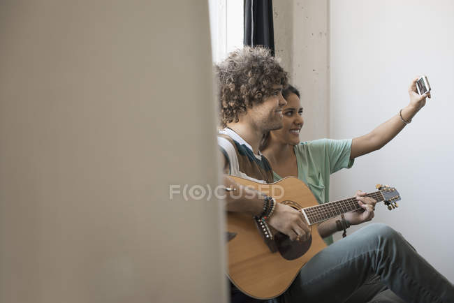 Мужчина играет на гитаре и женщина с телефоном — стоковое фото