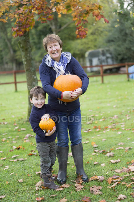 Mujer y un niño pequeño sosteniendo calabazas - foto de stock