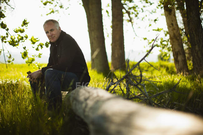 Uomo seduto su un tronco d'albero caduto — Foto stock