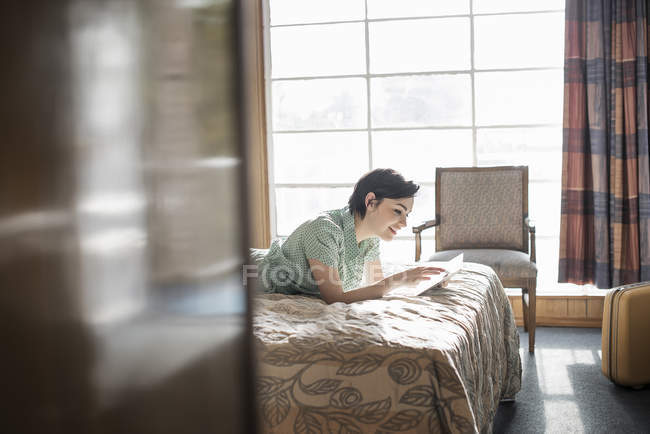 Mujer acostada en una cama en una habitación de motel - foto de stock