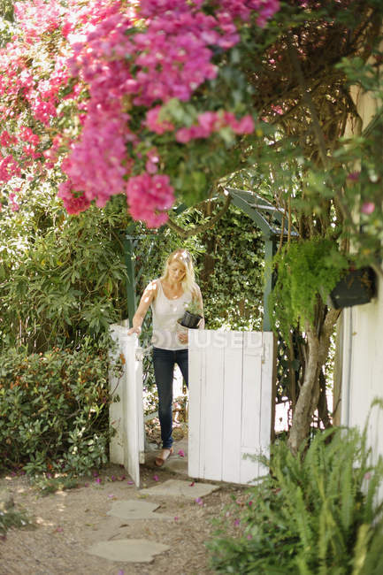 Donna che entra in un giardino attraverso il cancello — Foto stock