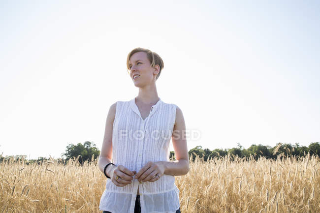 Jeune femme debout dans un champ de blé — Photo de stock