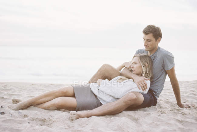 Пара, сидящая рядом на пляже — стоковое фото