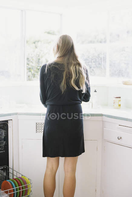 Жінка стоїть біля кухонної мийки . — стокове фото