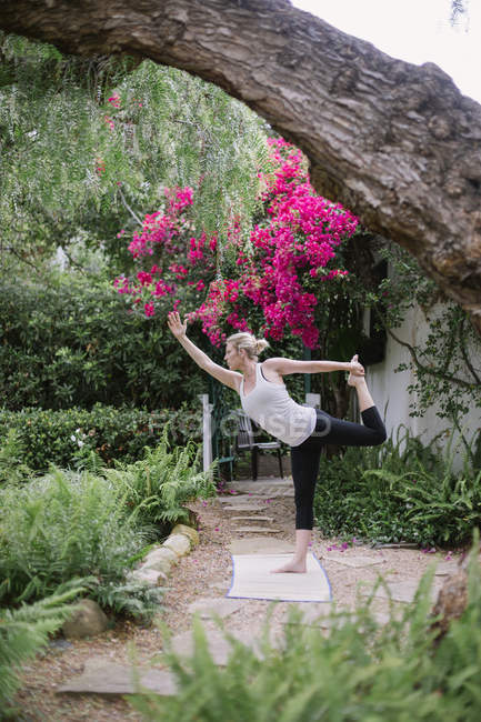 Frau macht Yoga im Garten. — Stockfoto