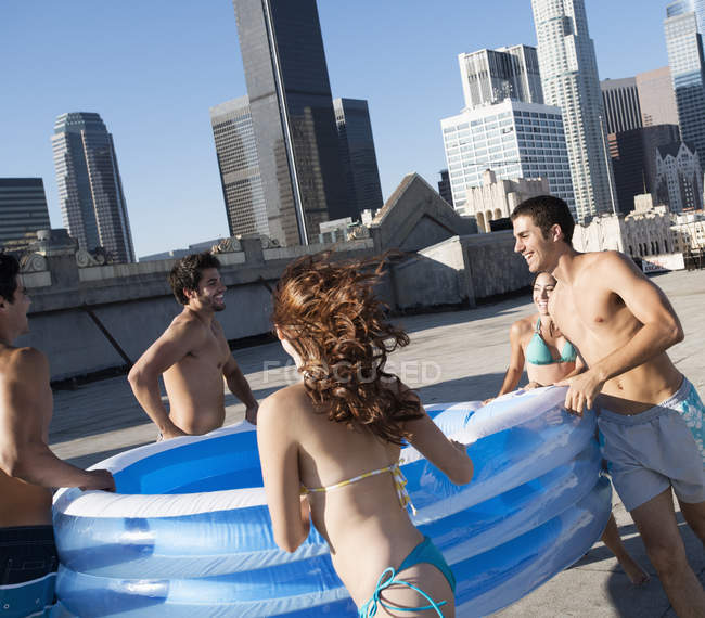 Amigos que carregam uma piscina de água inflável — Fotografia de Stock