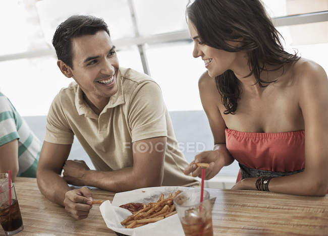 Casal compartilhando uma tigela de batatas fritas — Fotografia de Stock