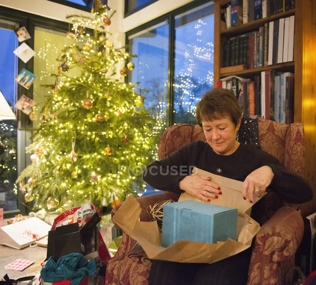 Mature woman unwrapping her presents — Stock Photo