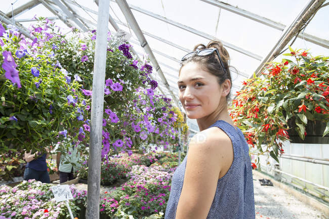Mujer de pie rodeada de plantas con flores - foto de stock
