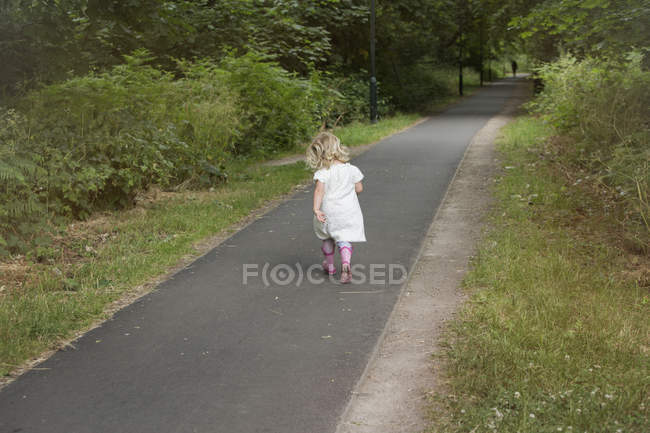 Chica joven caminando por un camino - foto de stock