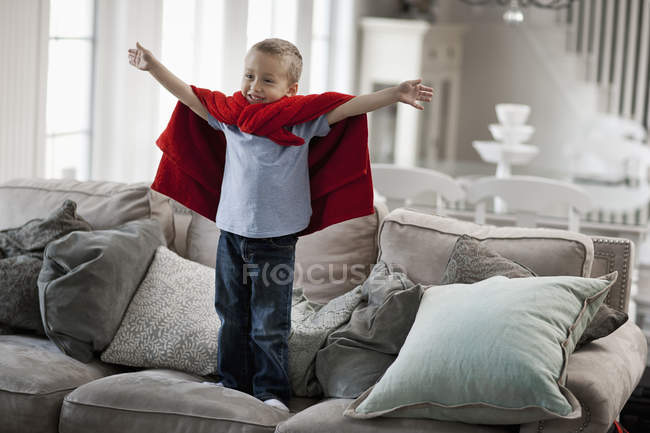 Niño con los brazos levantados en una pose de superhéroe . - foto de stock