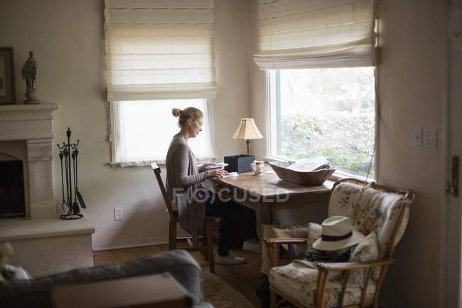 Woman sitting at a desk by a window — Stock Photo