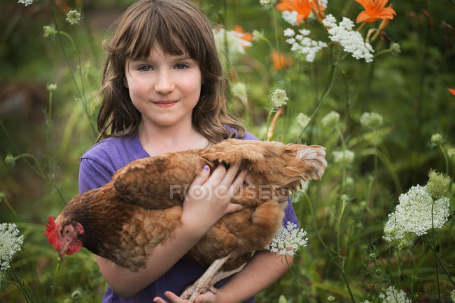 Jovencita sosteniendo una gallina doméstica - foto de stock