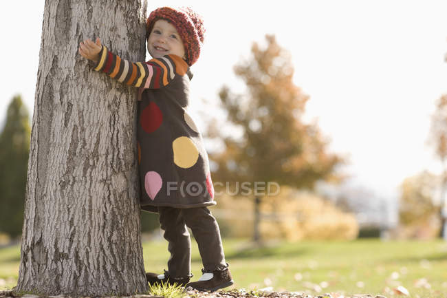 Chica con sus brazos alrededor de un árbol - foto de stock