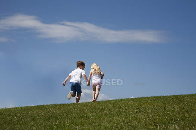 Niños corriendo por una colina - foto de stock