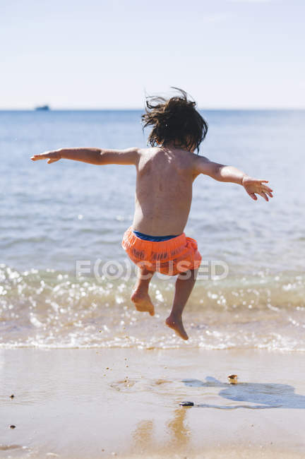 Хлопчик стрибає через хвилі — стокове фото