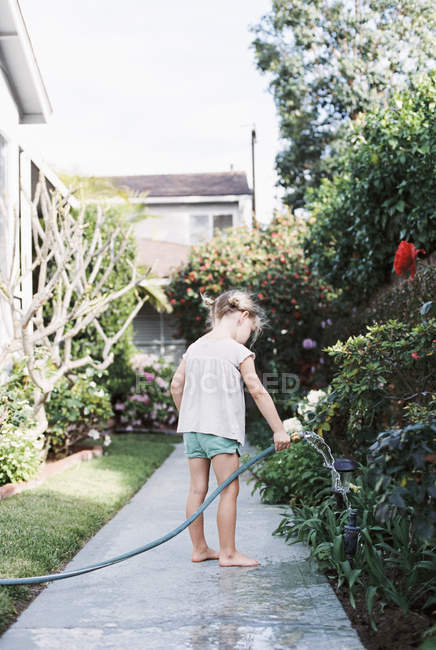 Chica de pie en un camino en un jardín - foto de stock