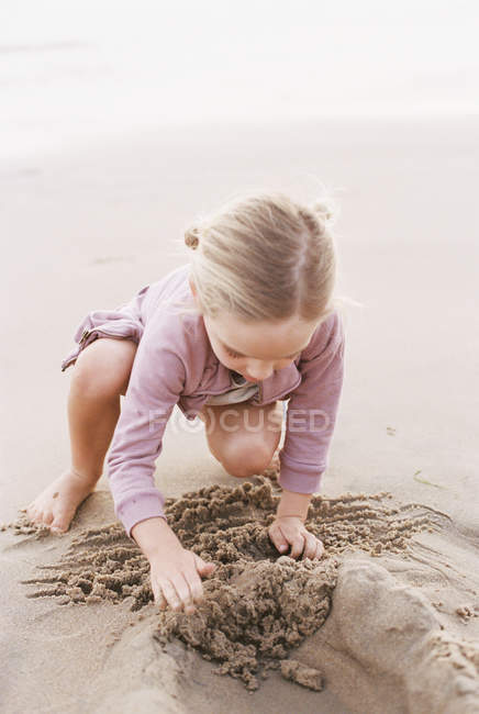 Молодая девушка играет на песке — стоковое фото