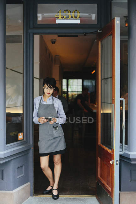 Waitress using smartphone — Stock Photo