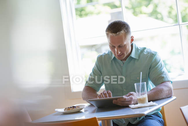Человек с помощью цифрового планшета в кафе — стоковое фото