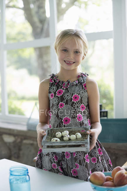 Chica con huevos de pájaro moteados en una caja . - foto de stock