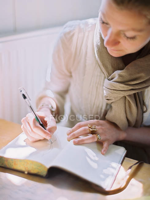 Mulher desenhando em uma página em branco de um diário . — Fotografia de Stock