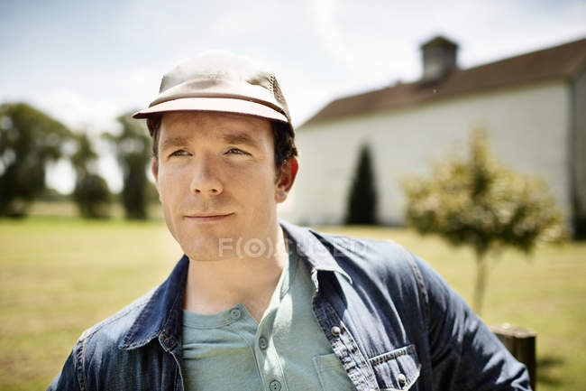 Uomo con un berretto da baseball in una fattoria biologica — Foto stock