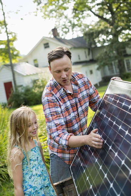 Pai e filha olhando para um painel solar — Fotografia de Stock