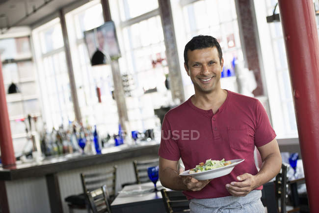 Male waiter serving a meal. — Stock Photo