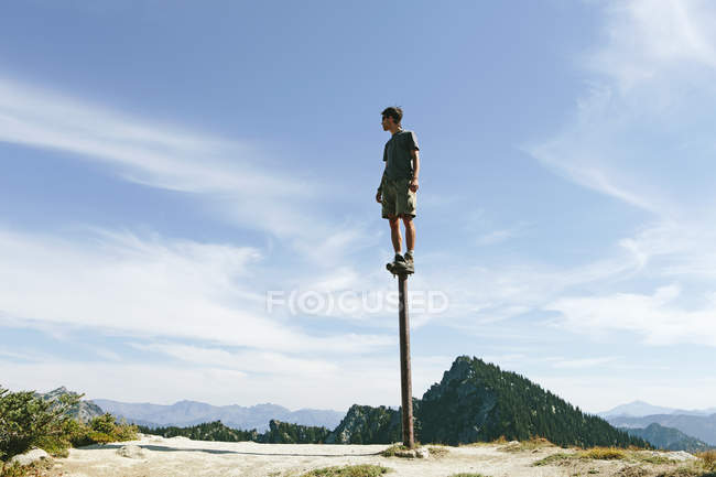 Uomo in piedi e bilanciamento su palo metallico — Foto stock