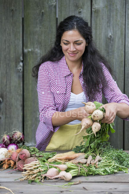 Жінка сортує свіжо підібрані овочі — стокове фото