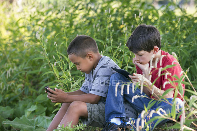Хлопчики використовують смартфон і цифровий планшет . — стокове фото