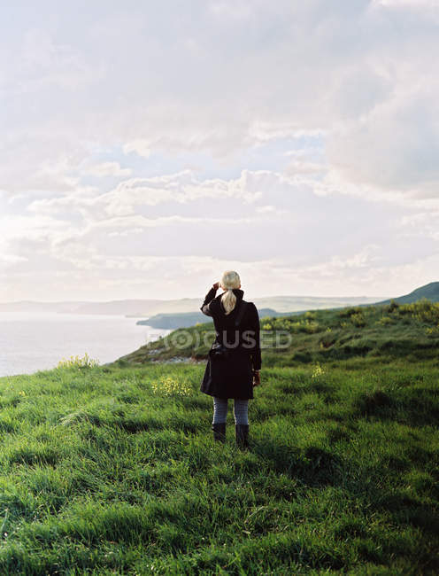 Woman looking along the coastline — Stock Photo
