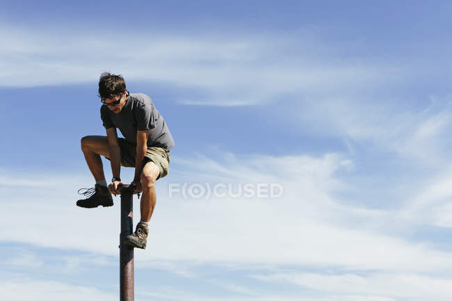 Man climbing on to top of metal post — Stock Photo