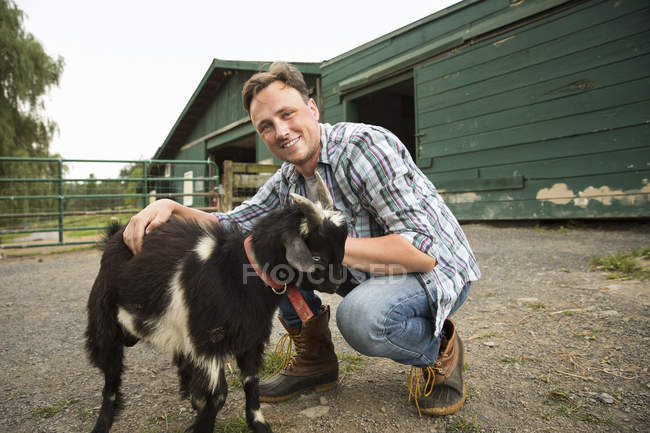 Hombre con pequeña cabra en halter - foto de stock