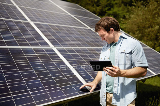 Agriculteur inspectant de près un panneau solaire — Photo de stock
