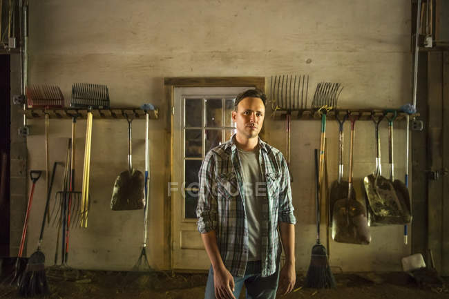 Hombre de pie en el granero con equipo - foto de stock