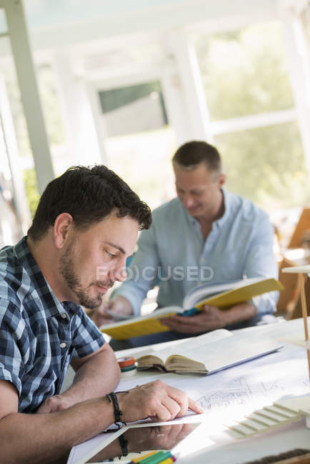 Men using books and a digital tablet. — Stock Photo