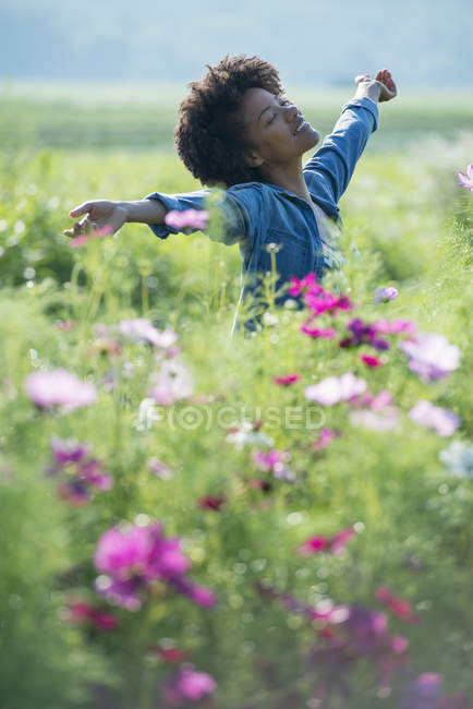Femme debout parmi les fleurs — Photo de stock