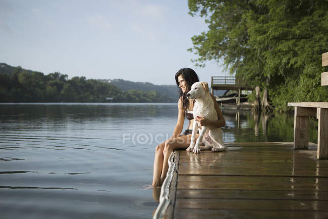 Mujer con perro blanco en embarcadero - foto de stock