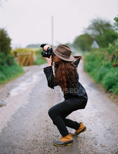 Mujer agachada para tomar una fotografía - foto de stock