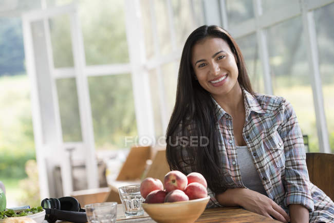 Glückliche Frau sitzt an einem Tisch. — Stockfoto