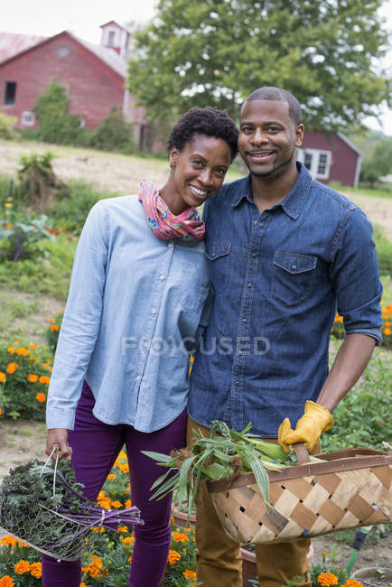 Couple portant des paniers avec des légumes — Photo de stock