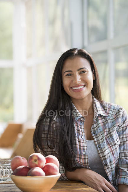 Mulher feliz sentada a uma mesa . — Fotografia de Stock