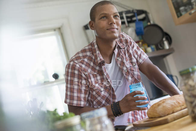 Man in a farmhouse kitchen with a glass — Stock Photo