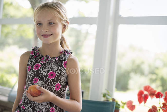 Menina segurando uma fruta de pêssego — Fotografia de Stock