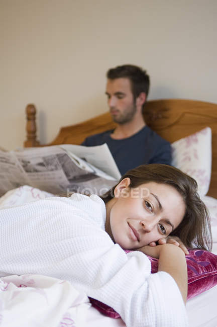 Жінка розслабляється і чоловік читає газету — стокове фото