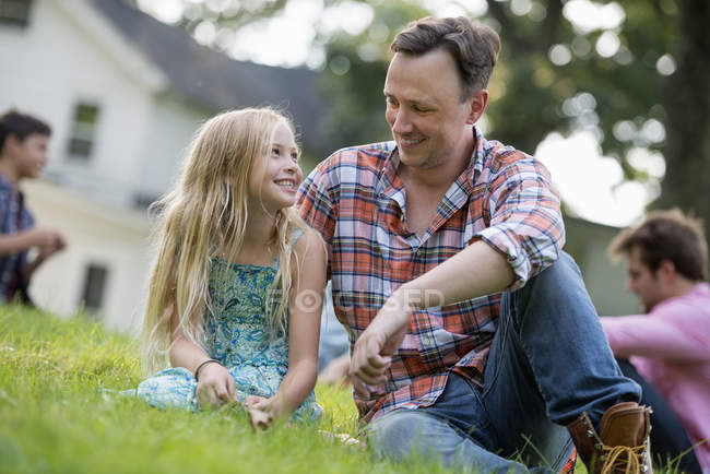Батько і дочка сидять на траві . — стокове фото